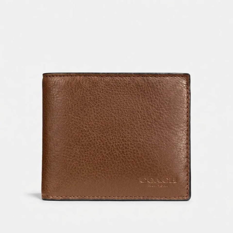 A brown pebbled leather bifold wallet with a debossed COACH logo on the bottom right, shown against a plain light gray background.