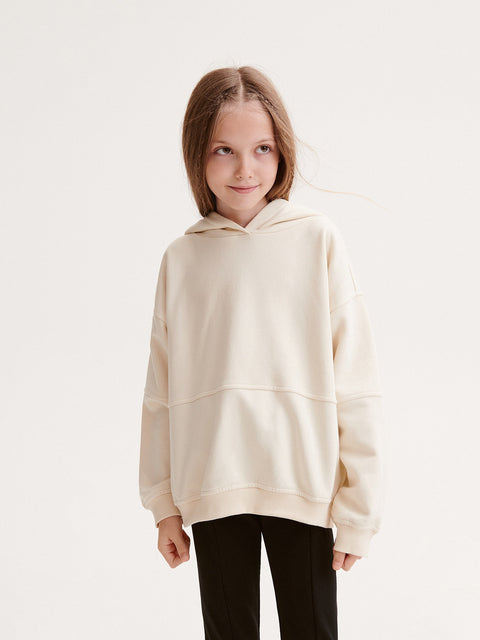 Child wearing a beige hoodie on a white background