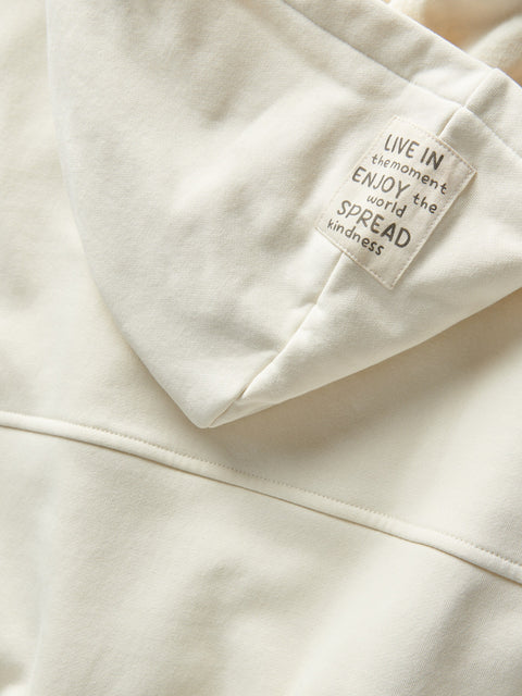 Close-up of a white hoodie with a motivational tag on a light background