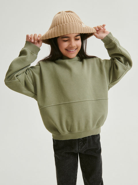 Person wearing a green hoodie and beige beanie on a plain background