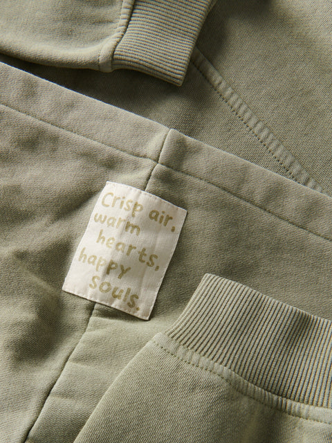 Close-up of a green sweatshirt with a text tag on the pocket.