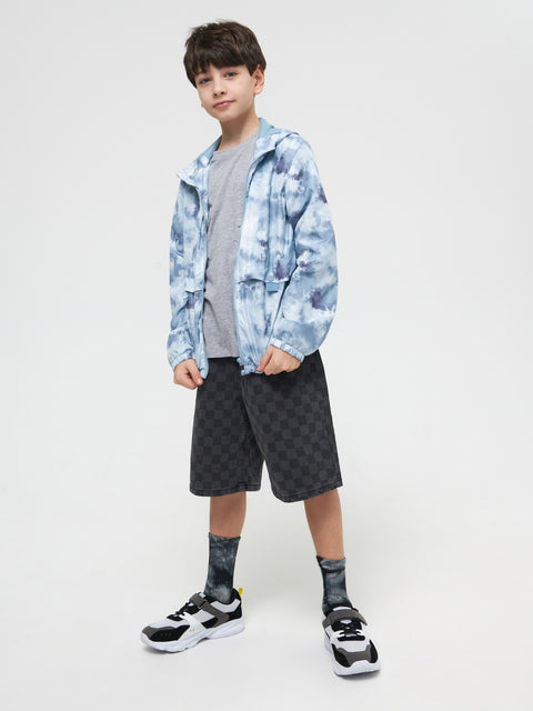 Child wearing a blue tie-dye jacket, gray shirt, black shorts, and sneakers on a white background
