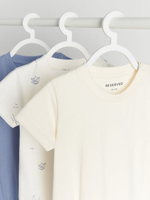 Three t-shirts on hangers with a 'Reserved' tag, one blue, one white, and one light gray.