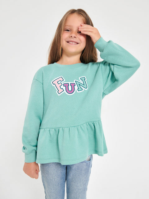 Girl wearing a light blue sweatshirt with 'FUN' printed on it against a white background