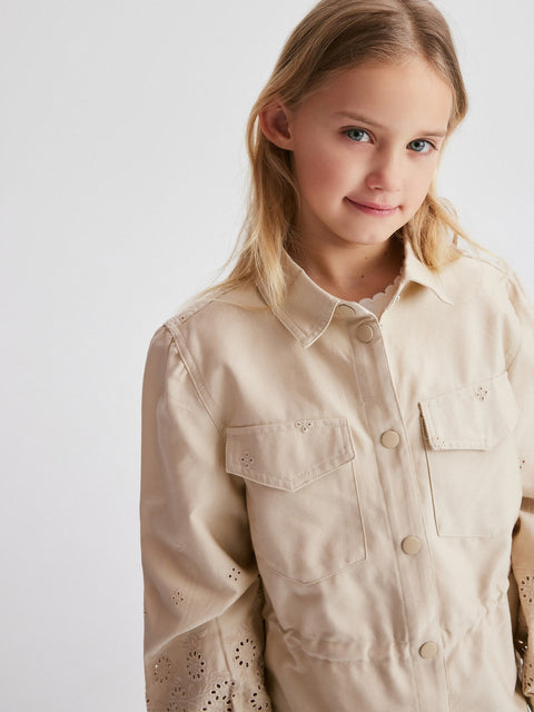 Young girl wearing a beige shirt with a plain background