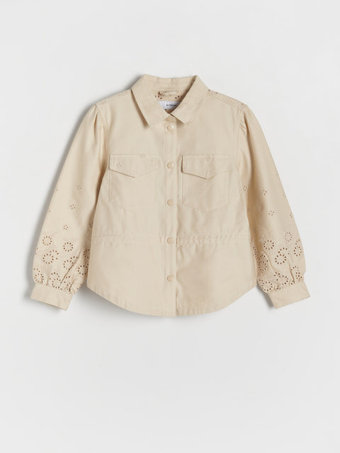 Beige shirt with floral embroidery on sleeves against a white background