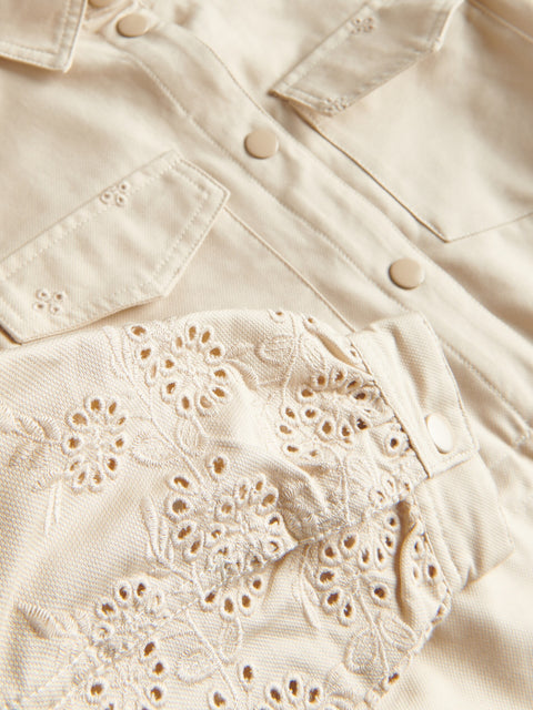 Close-up of a beige denim jacket with lace detailing