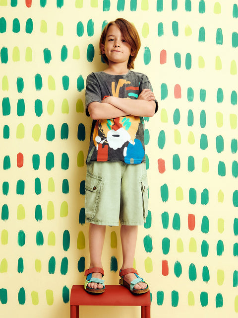 Child standing on a red stool against a colorful patterned wall