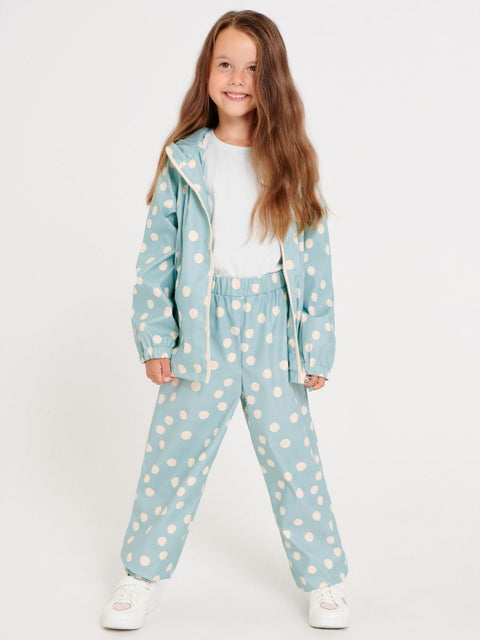 Young girl wearing a light blue polka dot outfit on a white background