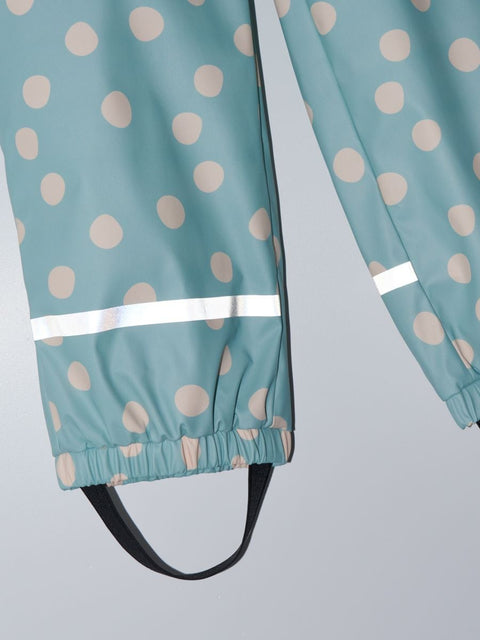 Teal raincoat with beige polka dots and reflective strip on a light gray background