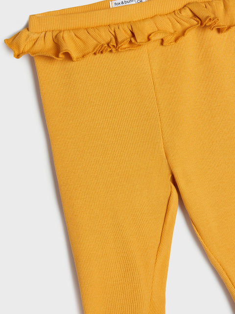 Mustard yellow leggings with ruffled waistband on a light gray background