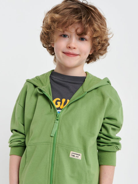 Child wearing a green hoodie with a visible brand label on a white background