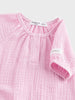 Close-up of a pink baby outfit with a label on a light gray background