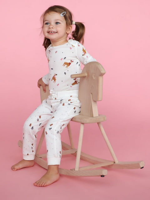 Child wearing a white outfit with animal prints on a pink background