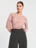 Woman wearing a pink lace top and gray pants on a white background