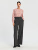 Woman wearing a pink lace top and gray wide-leg pants on a white background