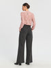 Woman wearing a pink lace blouse and gray pants on a white background