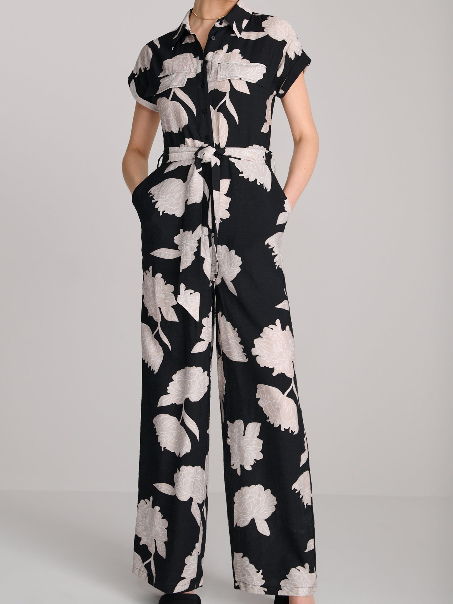 Black jumpsuit with white floral pattern on a gray background