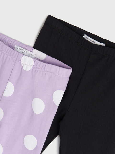 Two pairs of pants, one black and one with purple polka dots, on a light gray background.