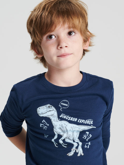 Child wearing a navy blue shirt with a dinosaur graphic and text on a plain background