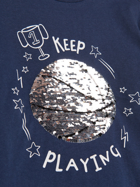 Navy blue t-shirt with sequin design and text 'Keep Playing' on a dark background