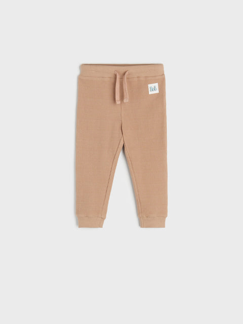 Beige baby pants with a brand label on a white background