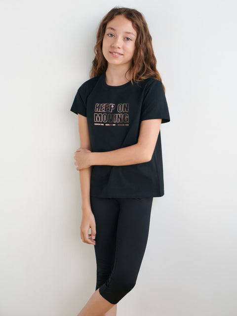 Young girl wearing a black t-shirt with 'Keep On Moving' text on a white background
