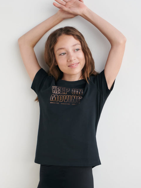 Young girl wearing a black t-shirt with 'KEEP ON MOVING' text on a white background
