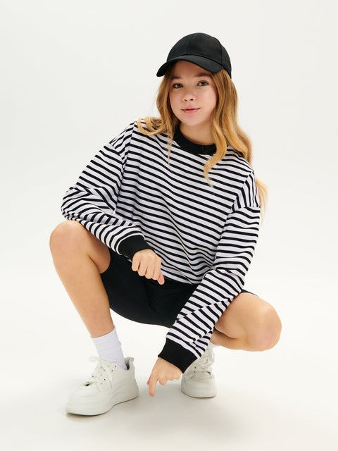 Person wearing a black and white striped sweater and black cap on a white background