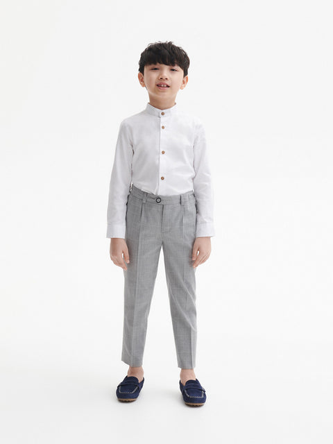 Young boy wearing a white shirt and gray pants on a white background