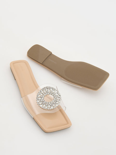 Beige sandal with a decorative brooch on a light gray background