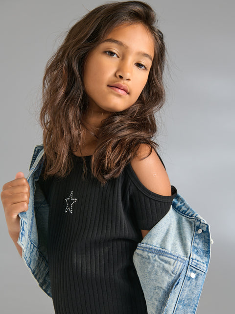 Young girl wearing a black top and denim jacket against a gray background