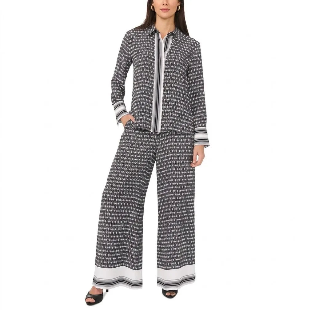 A woman modeling a matching two-piece lounge set featuring a long-sleeve button-front top and wide-leg pants, both in a black and white geometric pattern with striped cuffs and hems.