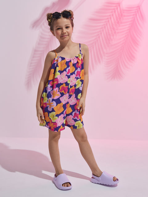 Young girl wearing a colorful floral dress against a pink background
