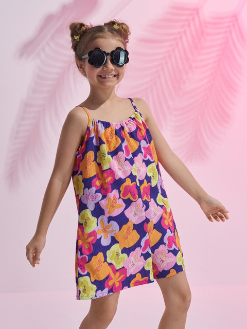 Young girl wearing a colorful floral dress against a pink background