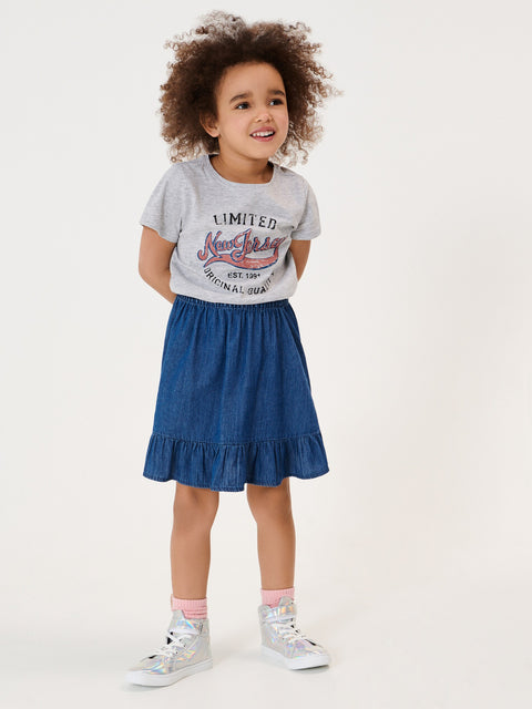 Child wearing a gray t-shirt with text and a blue denim skirt on a white background