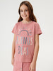 Young girl wearing a pink 'Buenos Dás' t-shirt on a white background