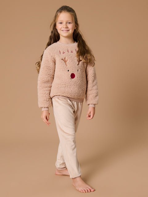 Young girl wearing a fluffy pink sweater with a reindeer design on a beige background