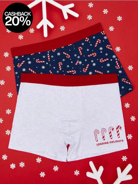 Two pairs of underwear with festive patterns on a red background with snowflakes and white deer antlers.
