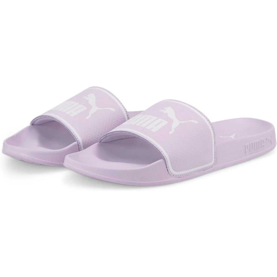 A pair of Puma slide sandals in a light lavender purple color, featuring a textured strap with a white Puma logo and a matching purple footbed.