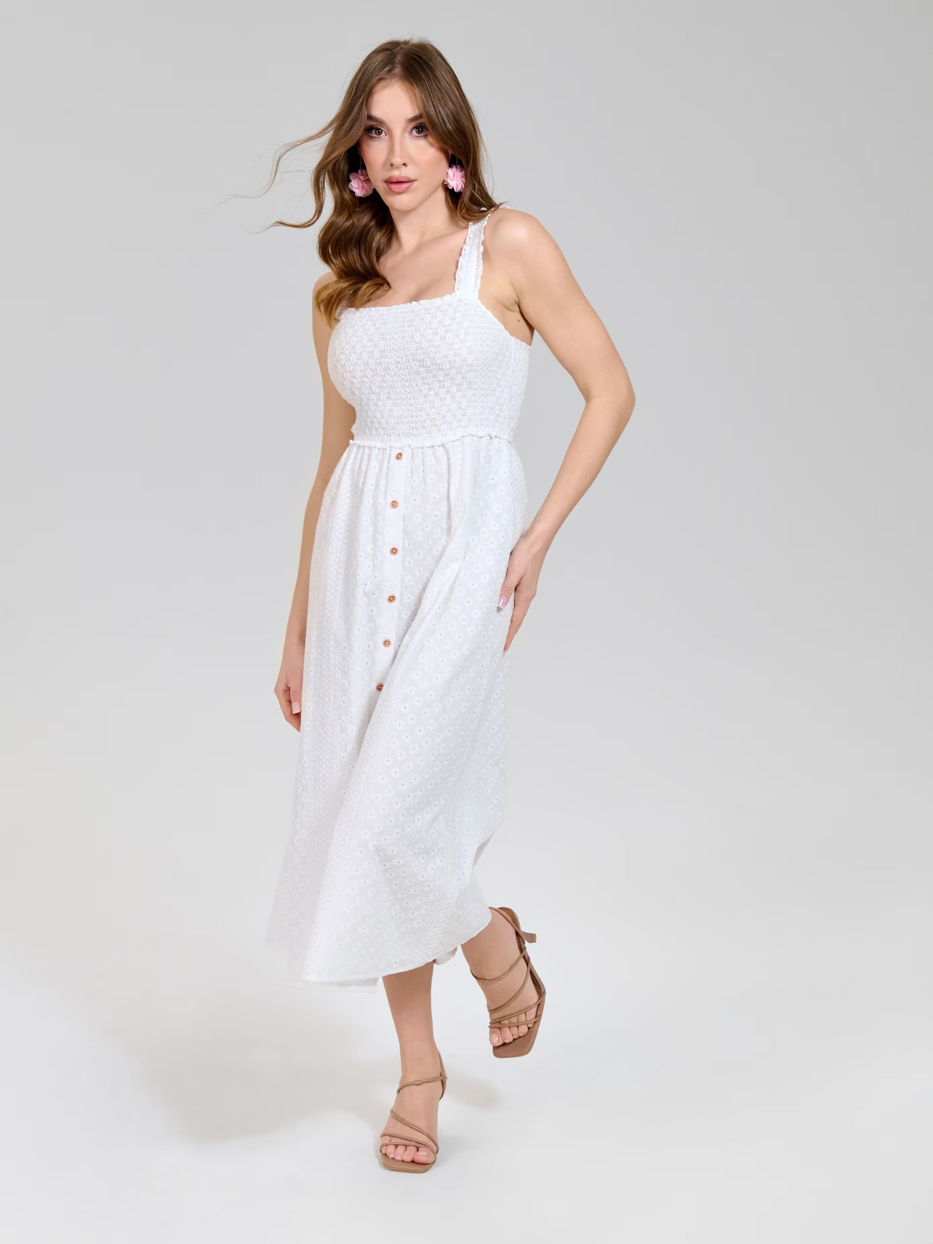 Woman wearing a white dress with buttons on a plain background