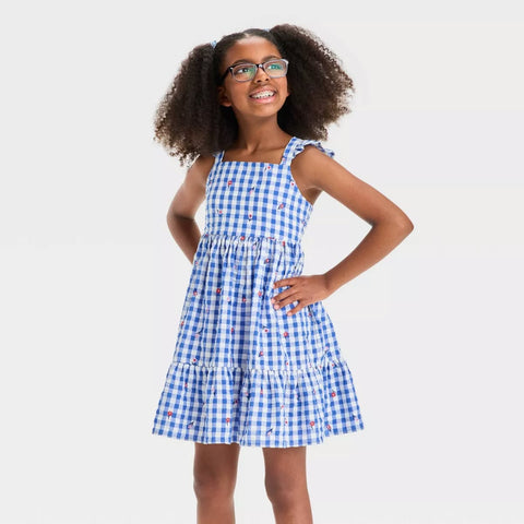 Girl wearing a blue checkered dress with a plain background