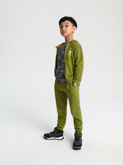 Child wearing a green tracksuit with a backpack on a white background