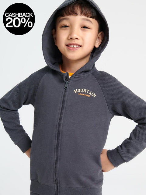 Child wearing a gray hoodie with 'Mountain Adventure' text on a light gray background