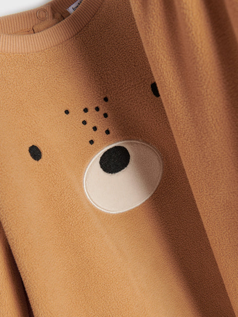 Close-up of a brown fleece garment with a bear face design.