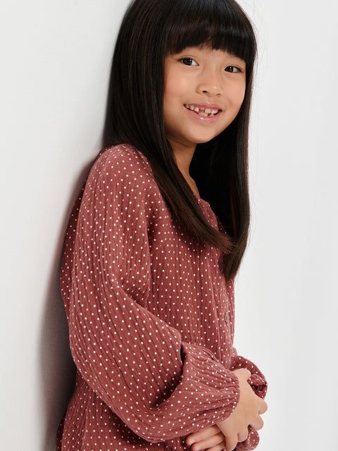 Young girl wearing a polka dot dress against a white background
