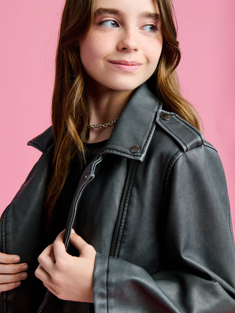 Person wearing a black leather jacket against a pink background