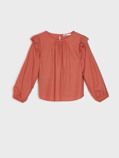 Terracotta-colored blouse with ruffled shoulders on a light gray background