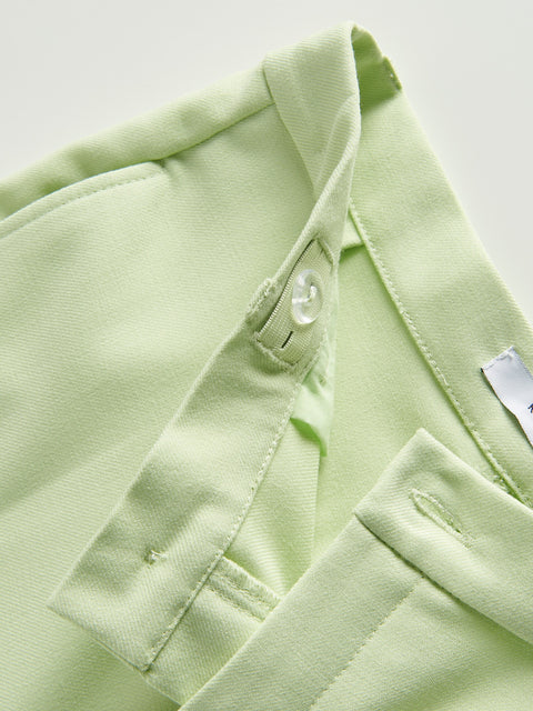 Close-up of a light green shirt with a button and tag on a white background