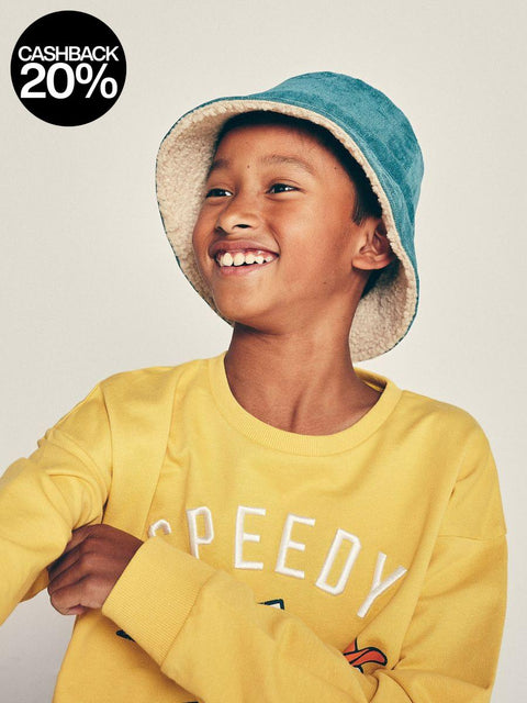 Child wearing a yellow sweatshirt with 'Speedy' text and a blue bucket hat on a plain background